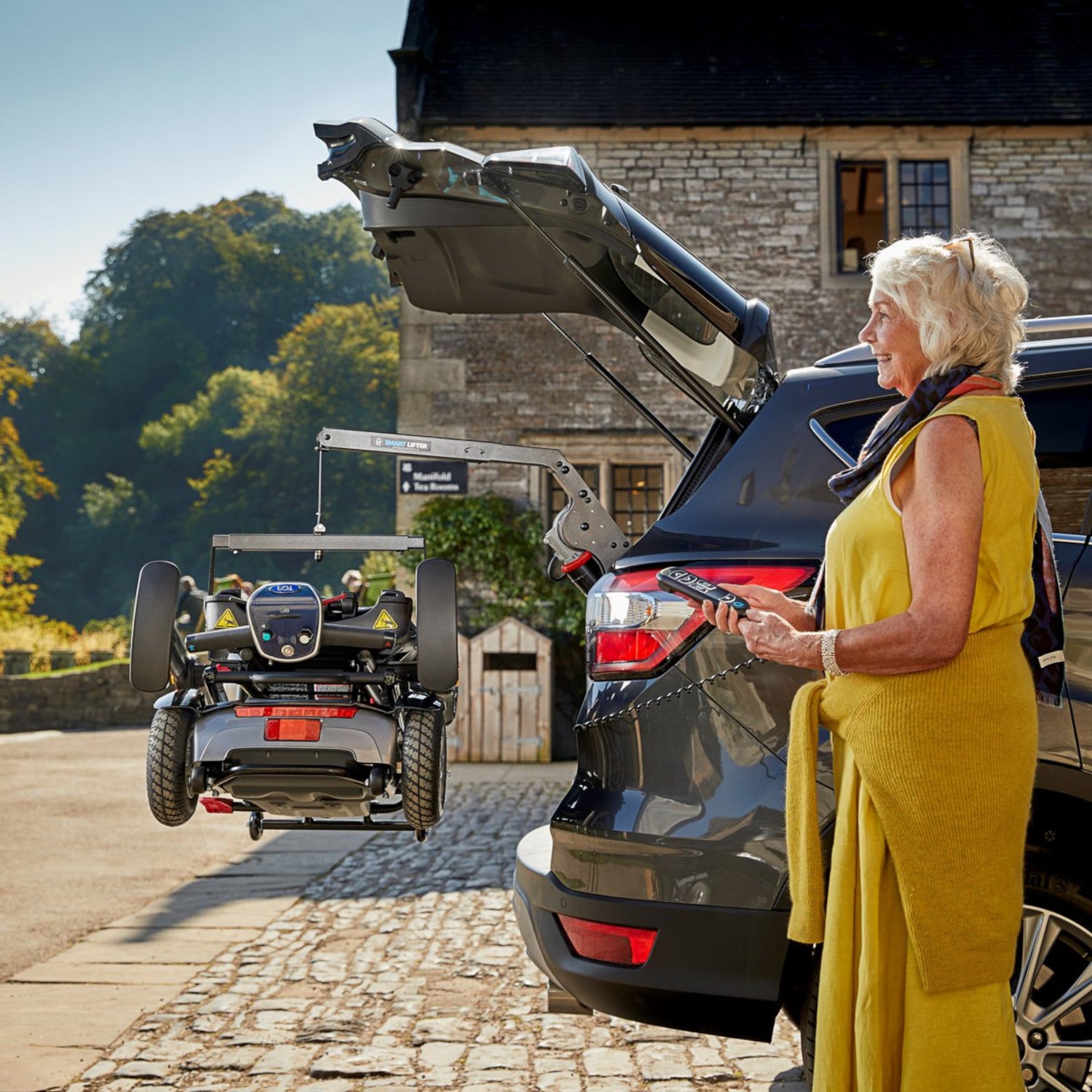 Woman operating Smart Lifter remote control, lifting scooter into the trunk of a car