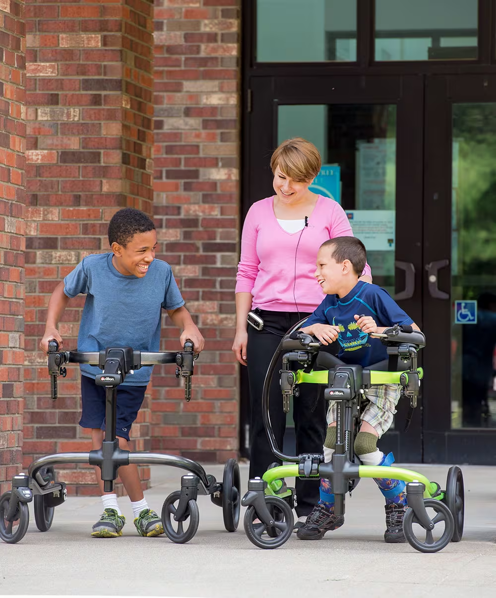 Two Children Using Rifton Pacer Gait Trainers Outside a Building